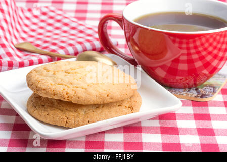 I biscotti al burro e un caffè nero in un bicchiere di rosso Foto Stock