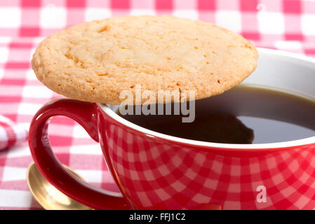 I biscotti al burro e un caffè nero in un bicchiere di rosso Foto Stock