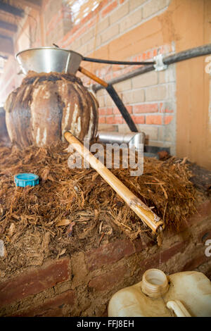 Santa Catarina Minas, Oaxaca, Messico - Distillato mezcal gocciolamenti da una canna di bambù in un tradizionale pentola di creta distilleria. Foto Stock