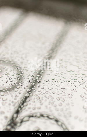 La condensa si forma di gocce di acqua su un vetro home finestra. Un cielo grigio in background con ringhiere consente un ampio spazio di copia per fare Foto Stock