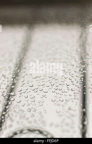 La condensa si forma di gocce di acqua su un vetro home finestra. Un cielo grigio in background con ringhiere consente un ampio spazio di copia per fare Foto Stock