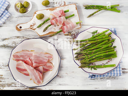 Asparagi freschi avvolto in pancetta su di un tavolo di legno. Vista superiore Foto Stock