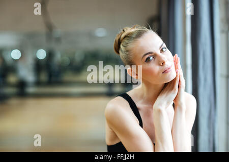 Giovane ballerina di riposo in classe di balletto e guardando la fotocamera Foto Stock