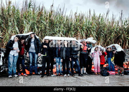 Volontari provenienti da diverse ONG internazionali dell offerta isoterma coperte e aiuto per i rifugiati che arrivano in barca flottante Foto Stock
