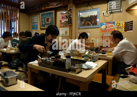 Popoli asiatici di mangiare in Tokyo, Giappone, Asia. La donna a pranzo nel tradizionale ristorante giapponese, la cottura di alimenti. I clienti, i clienti Foto Stock