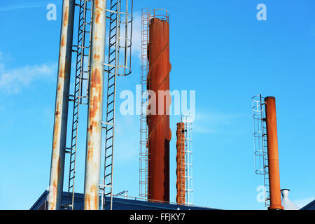 Un sacco di diversi camini contro un cielo blu. Alcuni il fumo proviene da uno di essi. Foto Stock