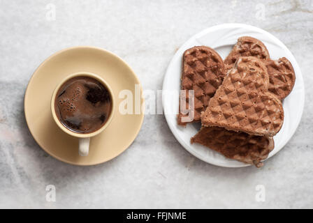 A forma di cuore e di cialde di caffè sul tavolo, dal di sopra Foto Stock