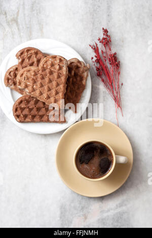 A forma di cuore e di cialde di caffè sul tavolo, dal di sopra Foto Stock