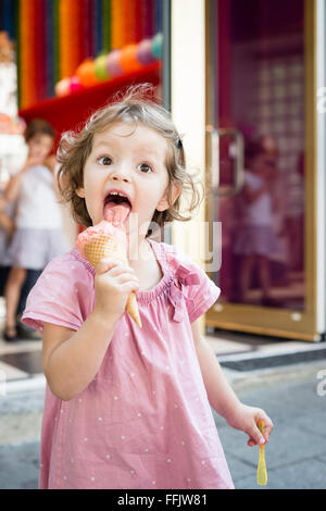 Bambina mangiare cono gelato all'aperto Foto Stock