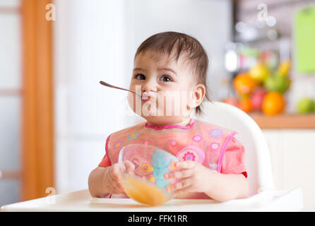 Sorridente baby a mangiare cibo da cucina Foto Stock