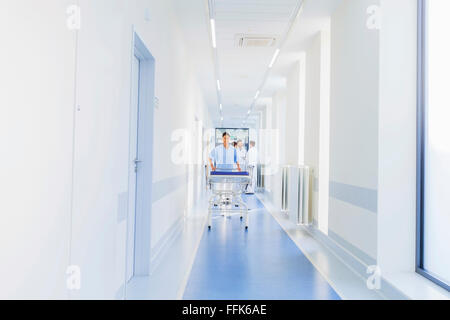 Lavoratore del settore sanitario ospedale di spinta barella in corridoio Foto Stock