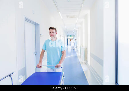 Lavoratore del settore sanitario ospedale di spinta barella in corridoio Foto Stock