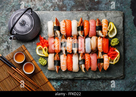 Set di sushi nigiri con tè serviti su pietra grigio ardesia su sfondo di metallo Foto Stock