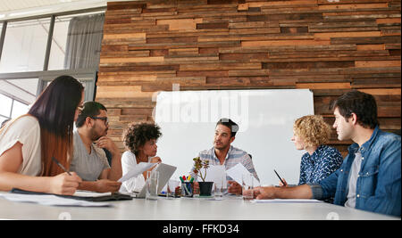 Gruppo di business persone aventi una riunione in una sala consiglio in un ufficio. Il team Creative seduti al tavolo per discutere nuova strategia Foto Stock