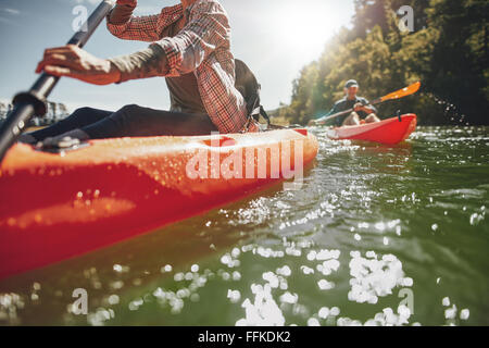 Immagine ritagliata della donna kayak con un uomo in background. Giovane canoa in un lago in un giorno di estate. Foto Stock