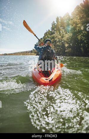 Immagine della vista posteriore di un uomo maturo canoa in un lago in una giornata di sole. Uomo senior di canoa kayak. Foto Stock