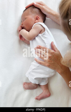 Sleeping neonato full lenght con le madri le mani Foto Stock