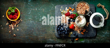 Sana colazione di muesli, frutti di bosco con yogurt e semi su sfondo scuro. Foto Stock