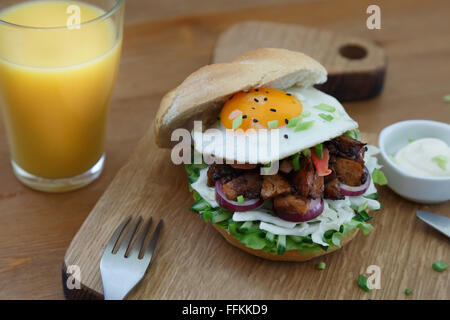 Hamburger fatti in casa con uova fritte e patatine fritte piccanti sul pannello di legno. Foto Stock