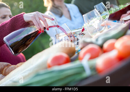 Versare il vino rosso in vetro su party in giardino Foto Stock