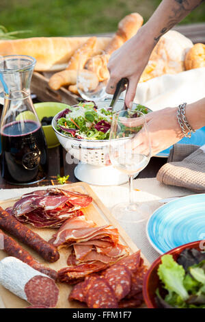 Giovane donna insalata di miscelazione sul party in giardino Foto Stock