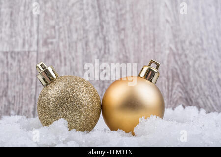 Due palle di Natale sulla neve con sfondo di legno Foto Stock