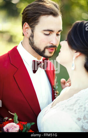 La sposa e lo sposo closeup, prima di Kiss, all'aperto, la tenerezza, la passione. Lo stile di nozze Marsala, ritratto verticale. Foto Stock