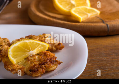 Cotoletta di pollo con spicchi di limone in piastra bianca Foto Stock