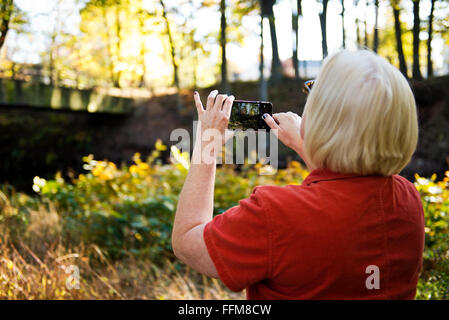 Donna prendendo un paesaggio foto con un telefono cellulare Foto Stock