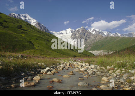 Piccolo ruscello e Tetnuldi, dalla valle al di sopra di Adishi, Mestia-Ushguli-Trek, Svaneti, Georgia Foto Stock