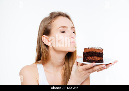 Bella carino donna giovane azienda pezzo di torta al cioccolato e invio un bacio su sfondo bianco Foto Stock