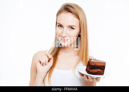 Attraente sorridente giovane donna mangiare pezzo di torta al cioccolato su sfondo bianco Foto Stock