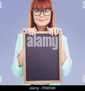 Immagine composita di sorridere hipster donna holding di Blackboard Foto Stock
