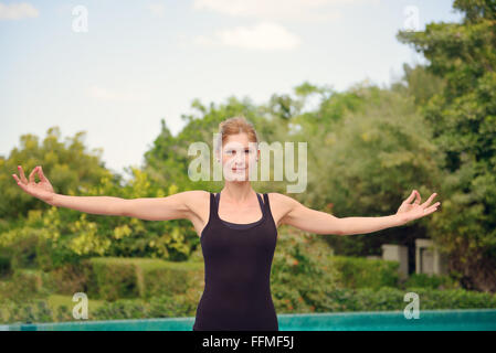 Donna fare yoga a bordo piscina a Dubai Foto Stock