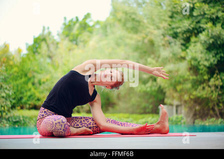 Donna fare yoga a bordo piscina a Dubai Foto Stock