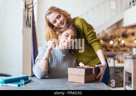 Donna che dono alla sua fidanzata in cafe Foto Stock