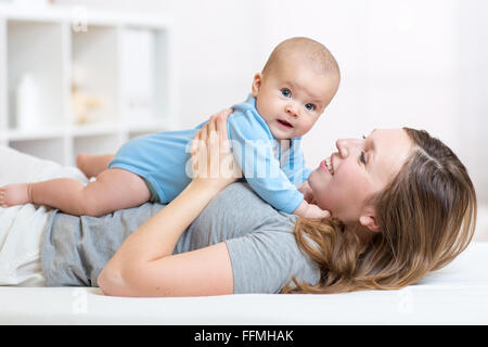 Baby e sorridente madre giacente a letto Foto Stock