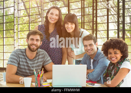 Immagine composita di felice creativo team di business riuniti attorno a un computer portatile Foto Stock