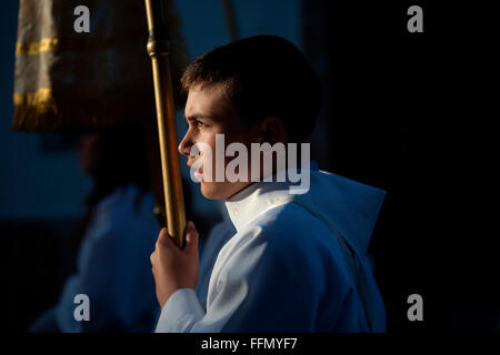 Un chierichetto detiene una candela durante una PASQUA SETTIMANA SANTA PROCESSIONE in Prado del Rey, Andalusia, Spagna Foto Stock