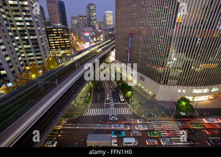 Un ampio angolo di visualizzazione e una lenta velocità di shutter cattura un il treno superveloce Shinkansen striature passato la Yurakucho Mullion edificio Foto Stock