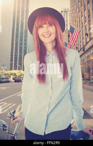 Immagine composita di sorridere hipster donna appoggiato su di una bicicletta Foto Stock