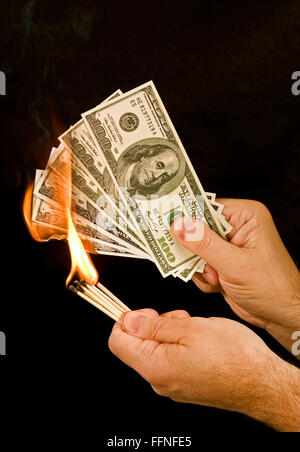 I soldi per masterizzare 1. Un uomo utilizza corrisponde per dare fuoco a un gruppo di un centinaio di fatture del dollaro. Foto Stock