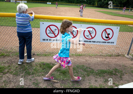 Giovane ragazza camminare da ballpark segni premonitori di mangiare congelati trattare ignaro al gioco in corso. St Paul Minnesota MN USA Foto Stock