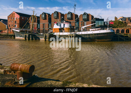 Fiume scafo ad alta marea con un obsoleto peschereccio nel fango bank affiancato da ufficio e di altri edifici di Hull, Yorkshire Foto Stock