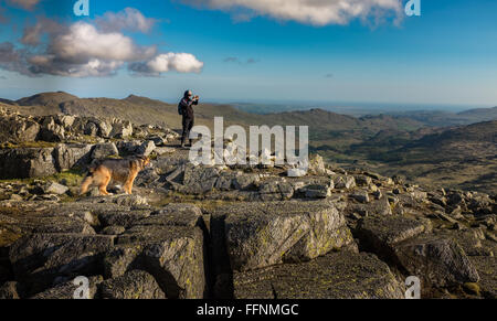 Un viandante sulla sommità del Bowfell nel distretto del lago, con il Langdales in background Foto Stock