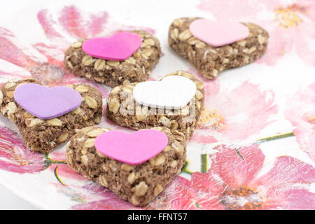 Heartshaped biscotti fatti da farina integrale su un vassoio decoupaged Foto Stock