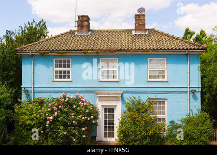 Blue country house con finestre bianche circondato da un lussureggiante giardino di rose e sulla porta anteriore. Foto Stock