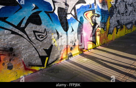 Ombra di un pedone proiettato su una parete piena di graffiti. Foto Stock