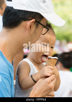 Asian padre e figlio sono mangiare gelati su vacanze estive. Candide foto di famiglia. Foto Stock