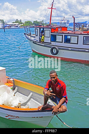 Giovane uomo su una barca al porto di Alotau su Milne Bay, Papua Nuova Guinea. Foto Stock